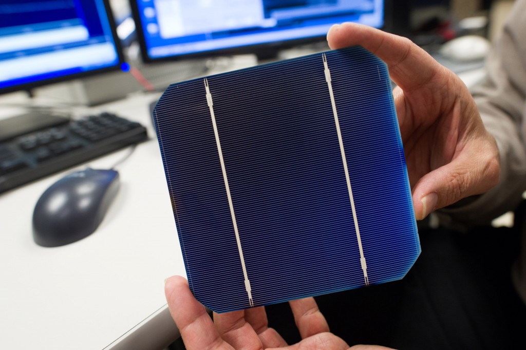 Figure 2. An NREL researcher holds an individual solar PV cell, the smallest light harvesting component in a solar PV system. Credit: Dennis Schroeder / NREL.