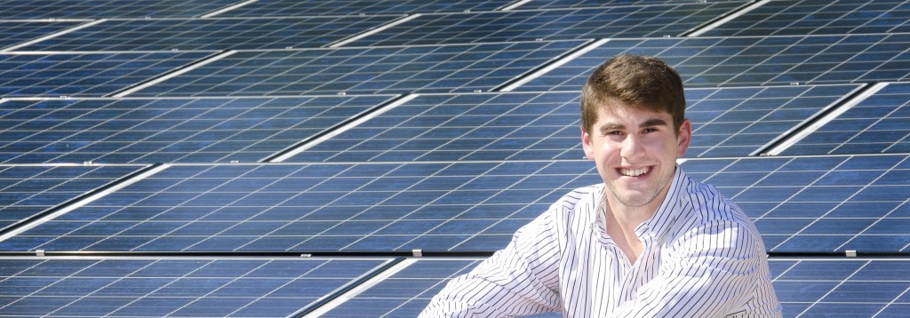 Figure 1. Stuart Block smiles in front of the 10.29 kW solar photovoltaic system installed on the roof of the Beta Theta Pi fraternity house on the University of Florida campus in Gainesville, FL. Credit: Eric Zamora/UF Photography.